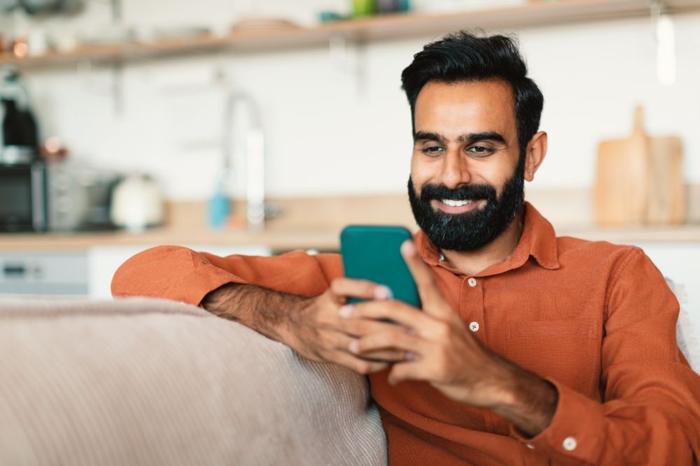 Happy Indian Bearded Guy Using Smartphone Texting RND4VD7